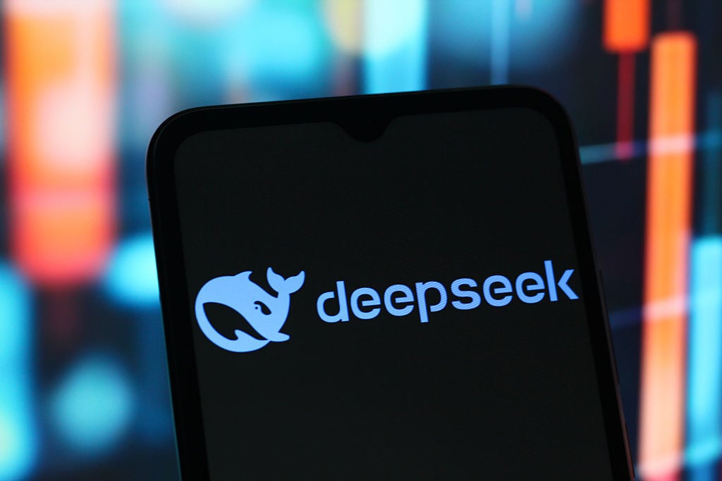 "Close-up of a smartphone displaying the 'deepseek' logo on a dark screen, with a blurred, colorful background."