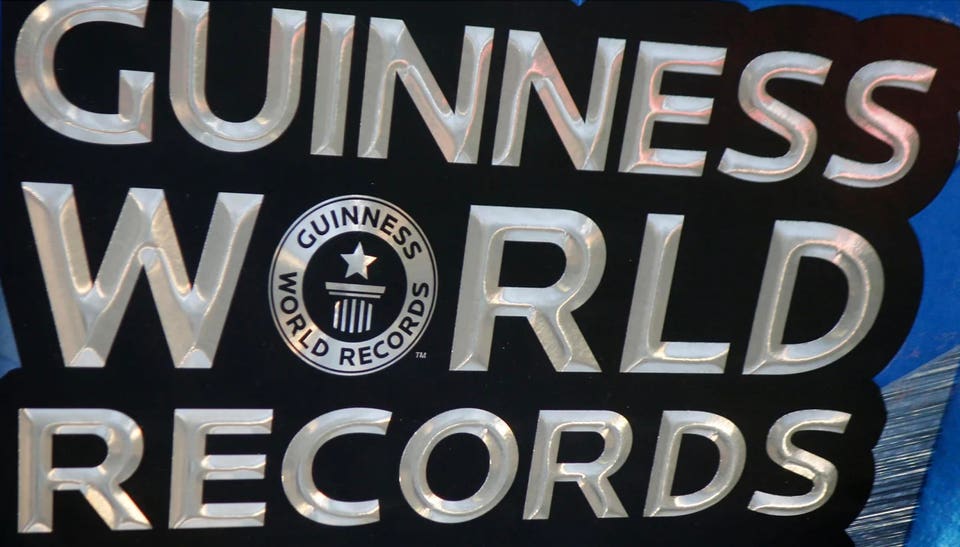 "Close-up of the Guinness World Records logo featuring stylized silver letters on a black background, accompanied by a circular emblem with a star and the text 'GUINNESS WORLD RECORDS.'"