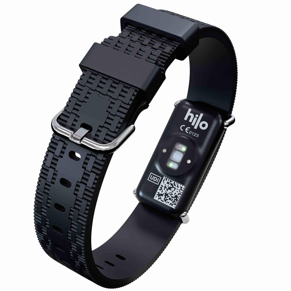 Black wearable health device with a textured strap and silver buckle, displaying its 'hilo' logo and green glowing sensors on the underside.