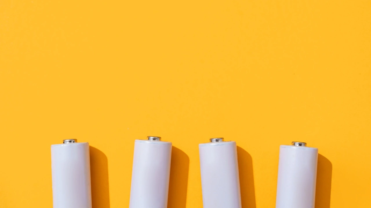 Four white batteries lined up against a yellow background.