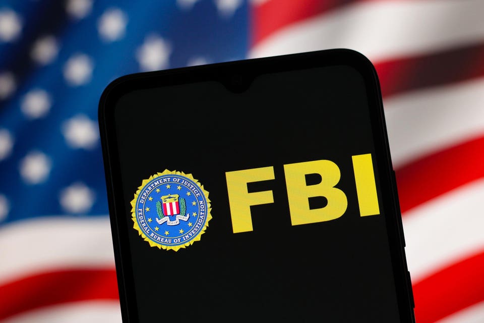FBI logo and text displayed on a smartphone screen with an American flag in the background.