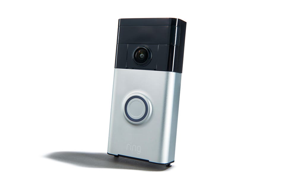 "A silver and black Ring video doorbell with a camera at the top and a circular button below it, resting on a white background with a shadow."