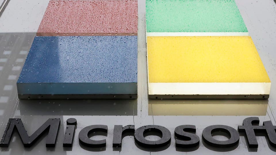 Microsoft logo sign featuring the four colored squares (red, blue, green, yellow) and the wordmark, wet with rain droplets.