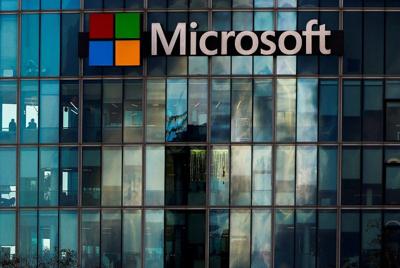 "Microsoft logo and name displayed on a modern building with reflective glass windows."