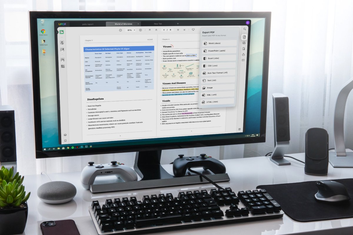 Computer monitor displaying the UPDF application with an open PDF document about microbes and an "Export PDF" menu, on a desk with a keyboard, mouse, and gaming controllers.