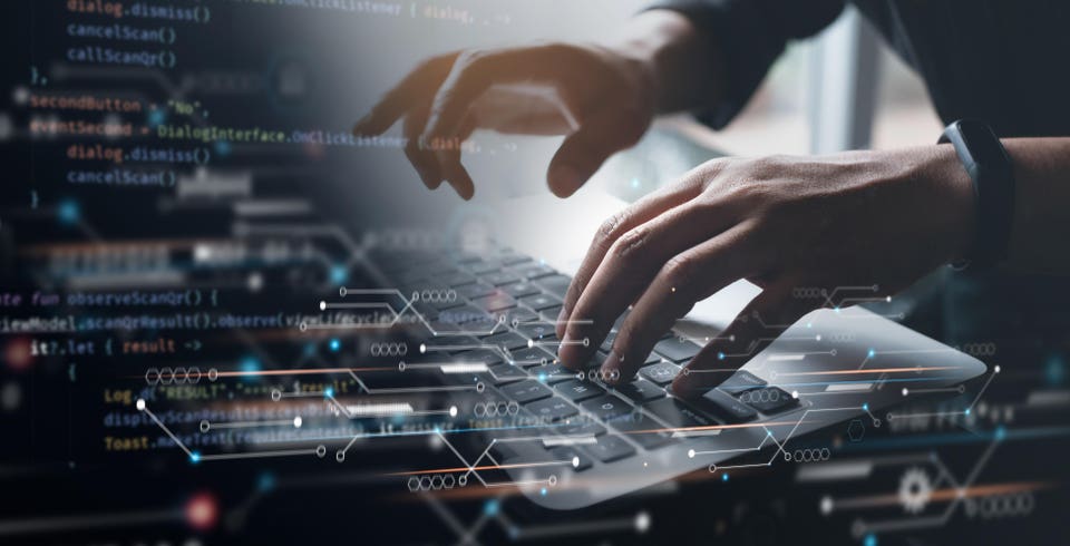 Hands typing on a laptop keyboard, with blurred programming code and glowing digital patterns overlaid.
