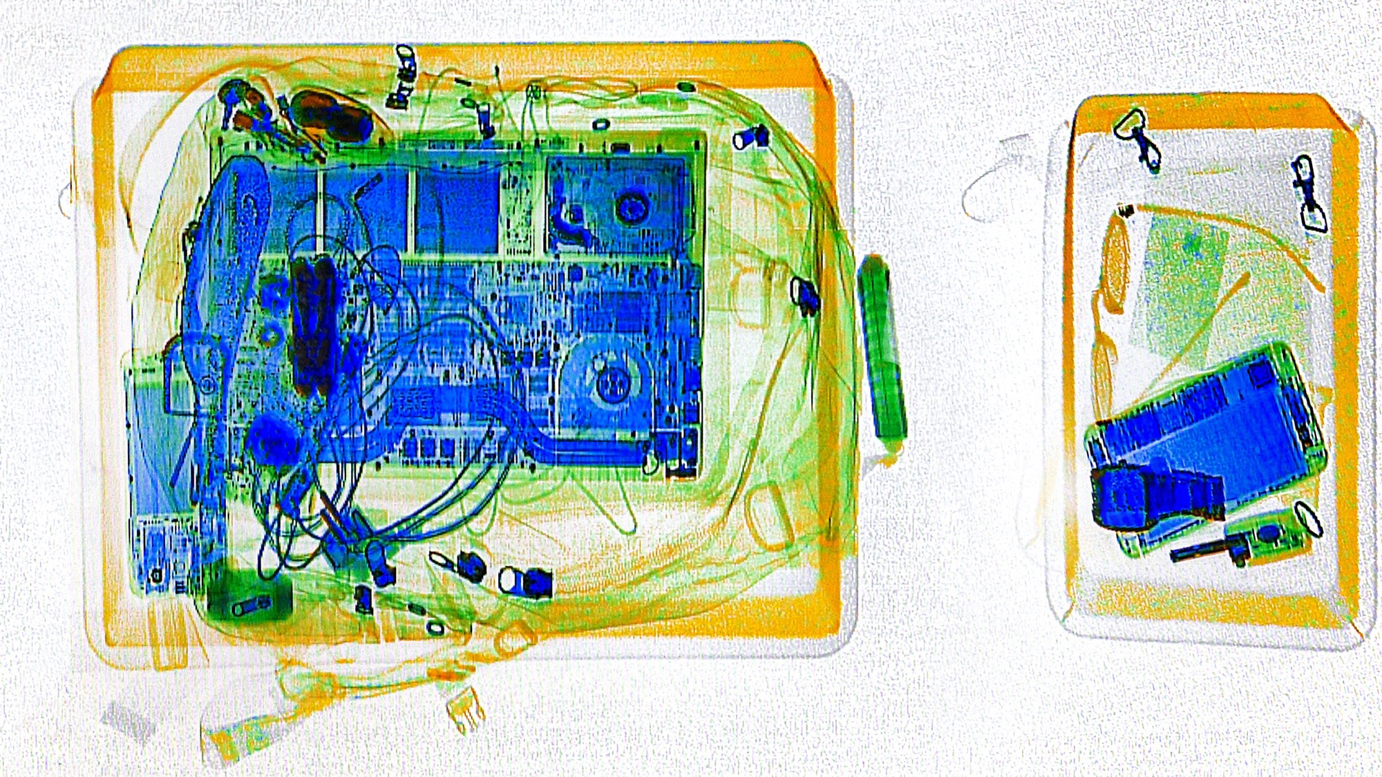 X-ray scan of two security trays, one containing a laptop and cables, the other a smartphone, a camera, and keys, with a water bottle nearby.