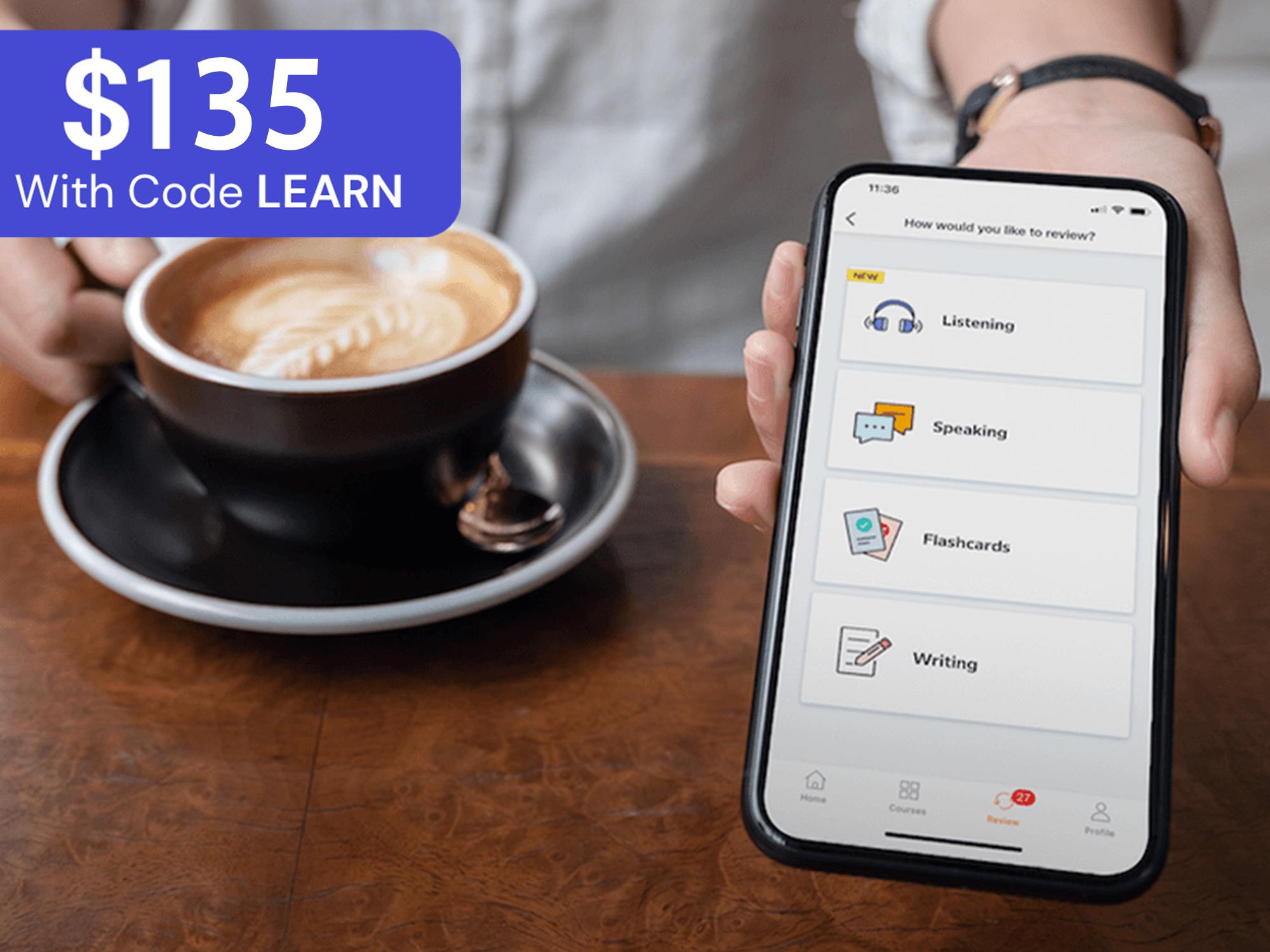 Person holding a smartphone displaying a language learning app with "Listening," "Speaking," "Flashcards," and "Writing" options, next to a coffee cup on a wooden table. A blue overlay displays "$135 With Code LEARN."