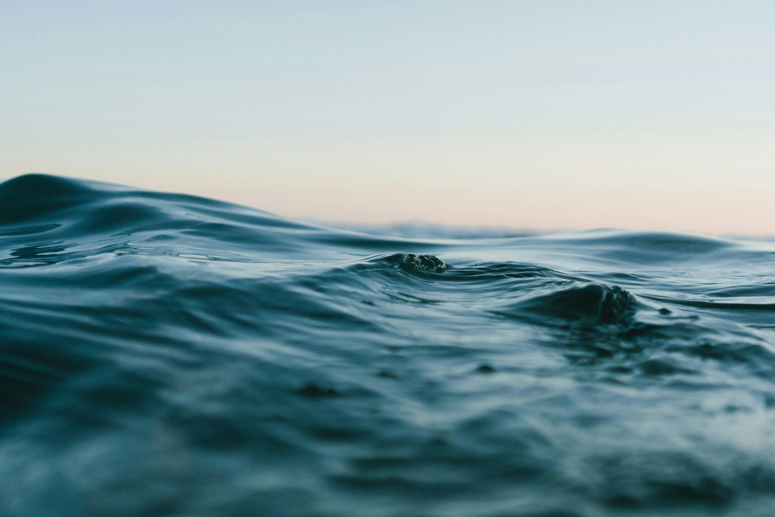 Close-up of deep blue rippling water with a soft, pale sky in the background.