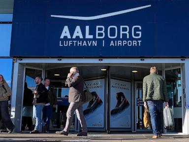 Aalborg Airport entrance with people walking through the doors under the blue sign.