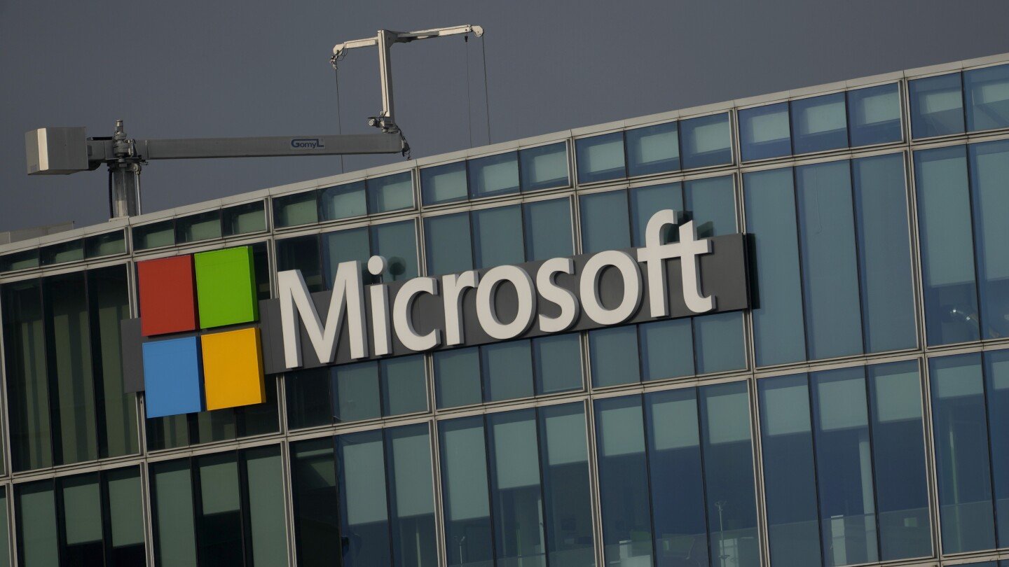 Microsoft logo with colorful squares and company name on a modern glass building.
