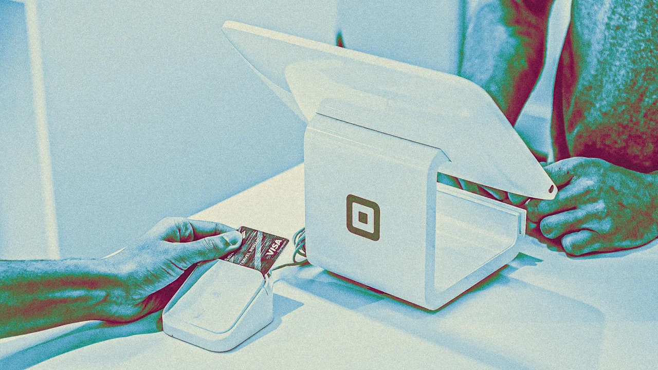 Hand inserting a Visa credit card into a card reader, with a Square point-of-sale system nearby.