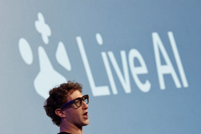 Mark Zuckerberg speaking in front of a screen displaying 'Live AI' and a stylized icon.