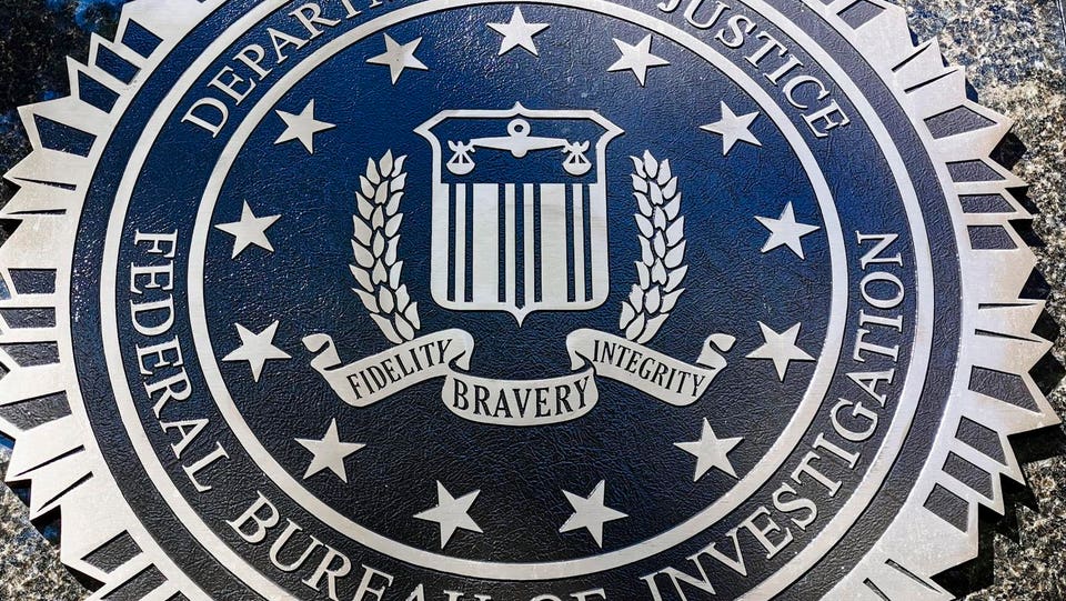 FBI seal, dark blue with silver text and emblems, displaying "FEDERAL BUREAU OF INVESTIGATION", "DEPARTMENT OF JUSTICE", and the motto "FIDELITY BRAVERY INTEGRITY".