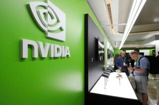 NVIDIA logo and name on a green wall at an event booth, with people browsing displays.