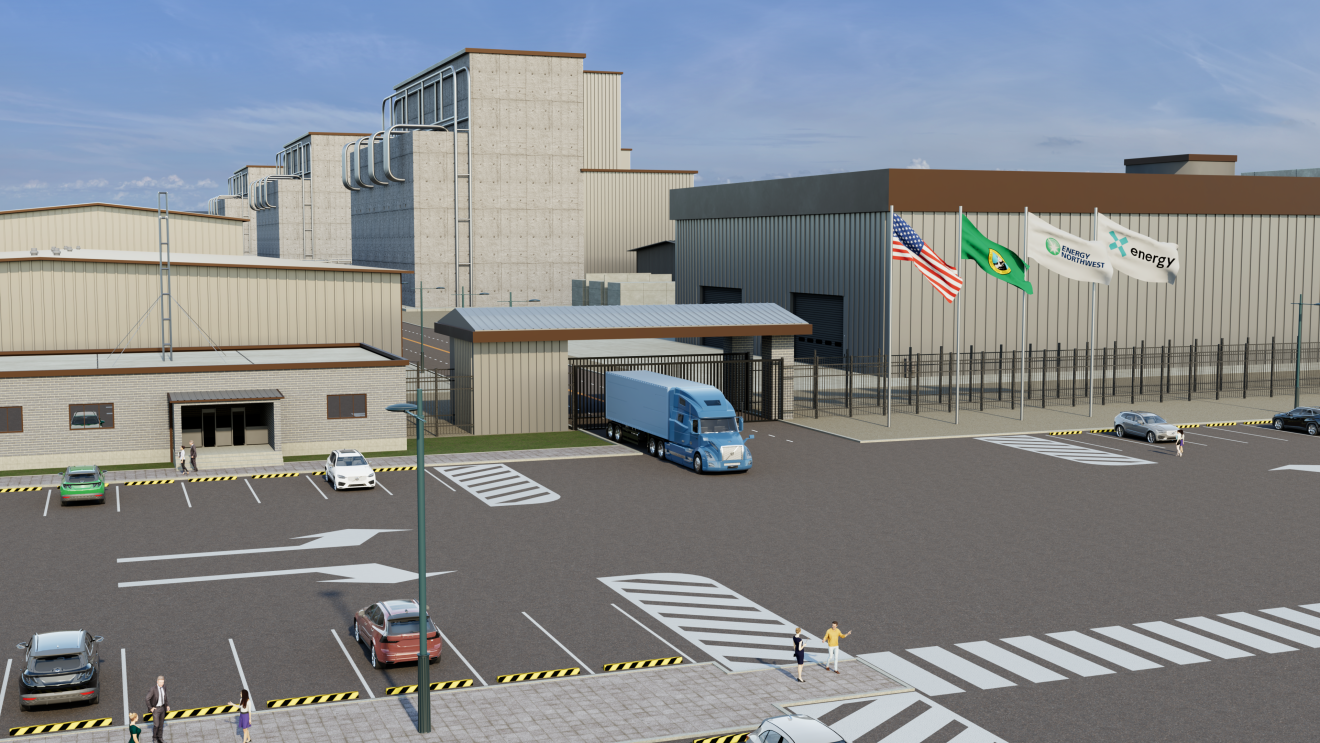 Industrial complex with concrete utility buildings and metal warehouses, a parking lot with cars, and a blue semi-truck at a guarded gate. Flags for the USA, Washington state, and Energy Northwest are flying.