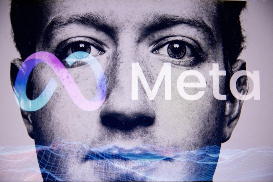 Close-up of Mark Zuckerberg's face with the Meta infinity logo overlaid in blue and purple, the word "Meta" in white, and a blue digital wireframe pattern across his mouth and chin.