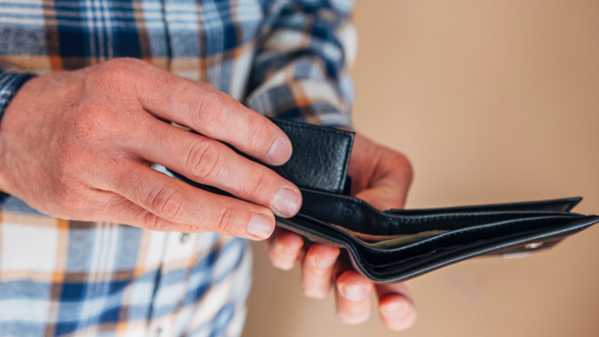 "A person's hands holding an open, nearly empty black wallet."