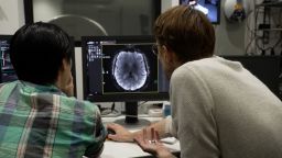 Two people examining a computer monitor displaying a brain scan.