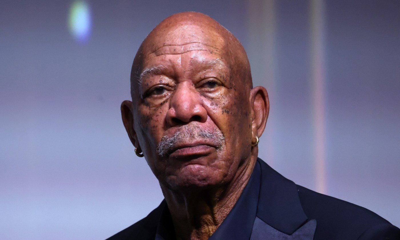 "Close-up of Morgan Freeman with a thoughtful expression, wearing a dark suit and gold hoop earrings."